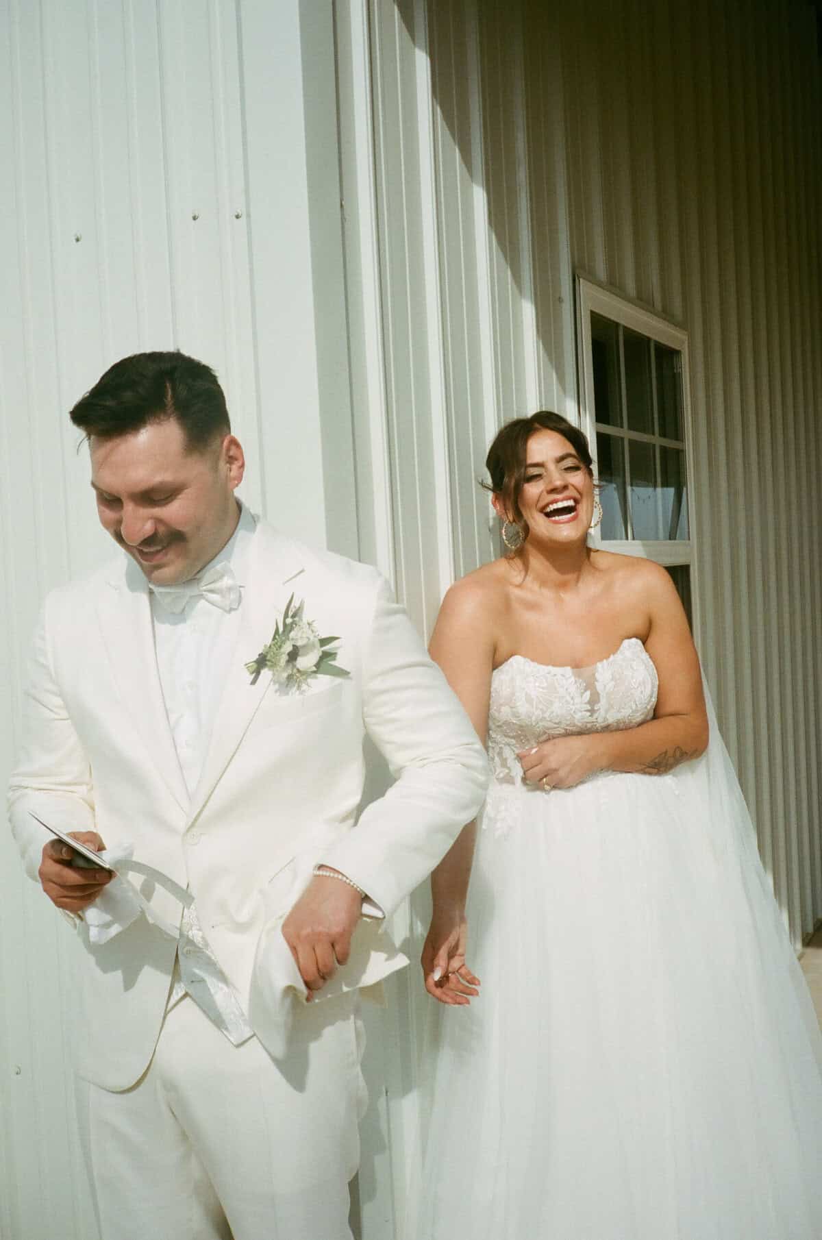 bride and groom in all white laughing on their wedding day